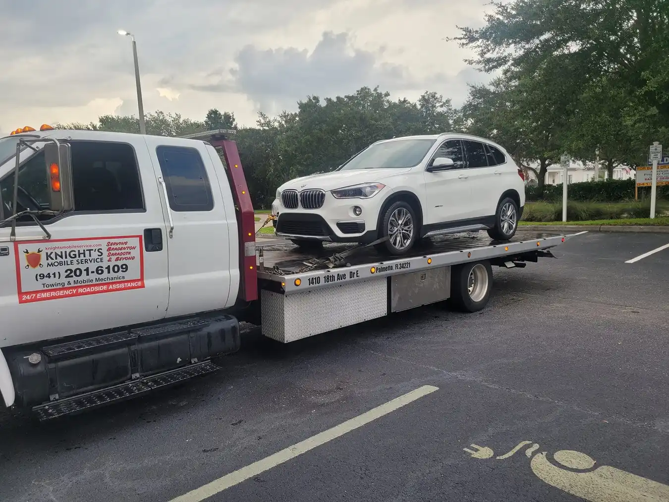 Knights Mobile Service flatbed towing a white BMW SUV in Manatee County