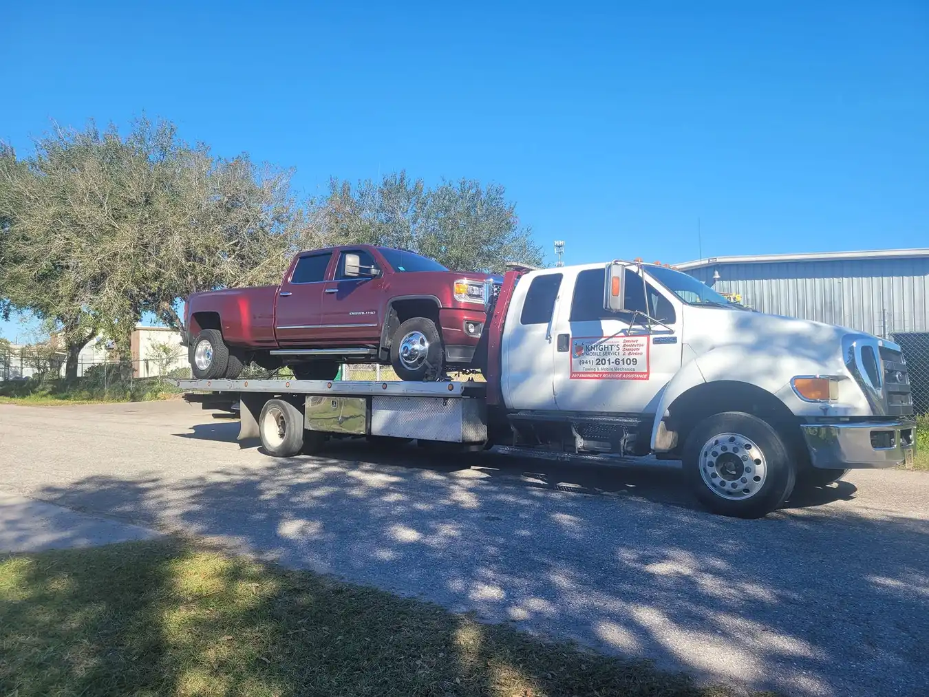 Red pickup secured on a Knights Mobile Service flatbed tow truck